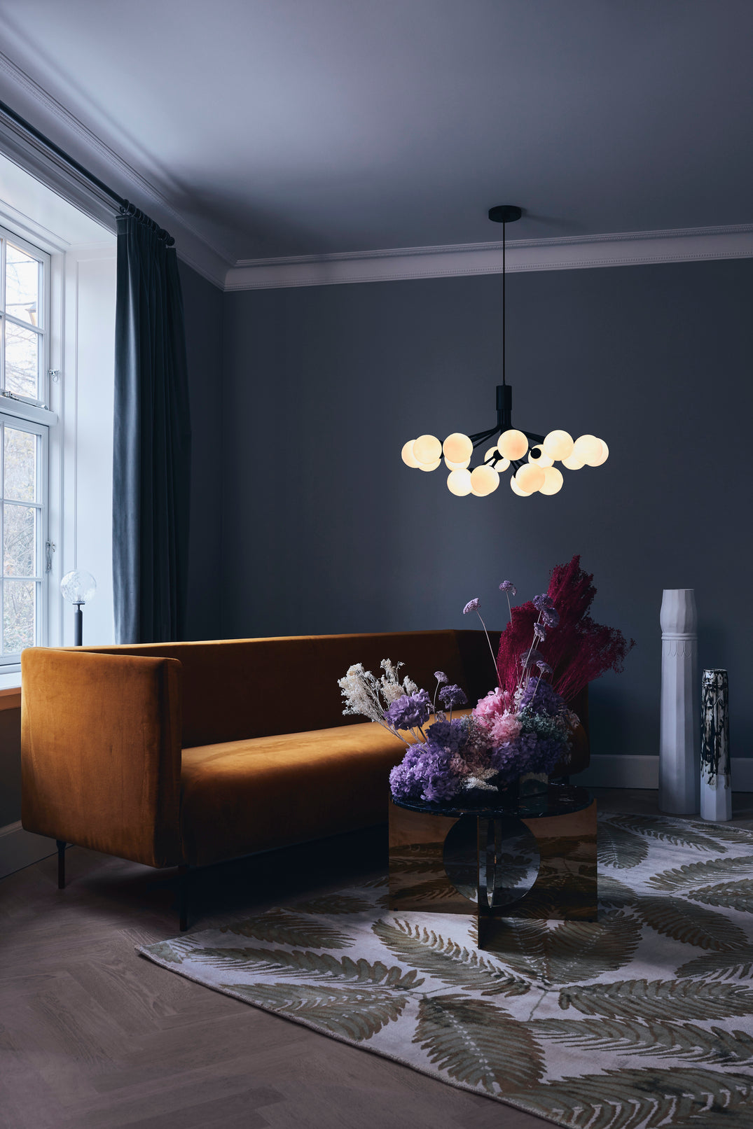 Lysekrone bestående af runde skærme i opalglas samt sort krone, i dagligstuemiljø