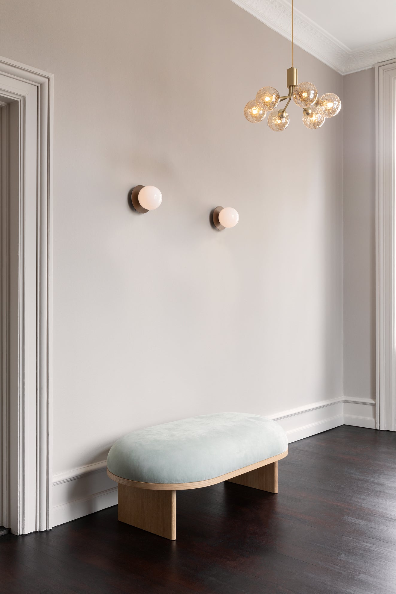 Lysekrone bestående af runde skærme i gyldent optikglas samt messingfarvet krone, pi dagligstuemiljø