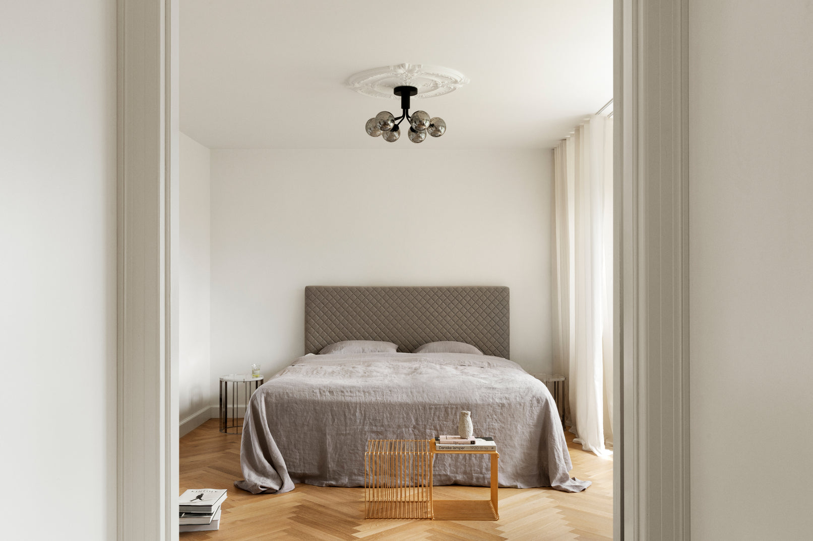 Lysekrone bestående af runde skærme i røgfarvet optikglas samt sort krone, i soveværelse