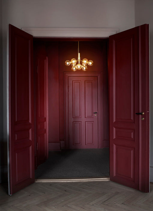 Lysekrone bestående af runde skærme i gyldent optikglas samt messingfarvet krone, i entre