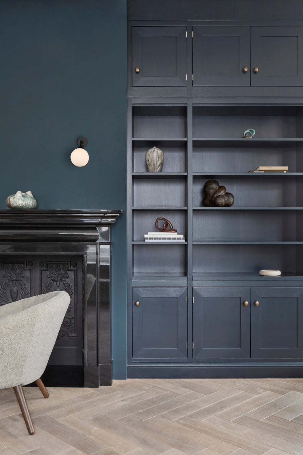 Væglampe med rund skærm af opalglas og sort stel, i dagligstuemiljø