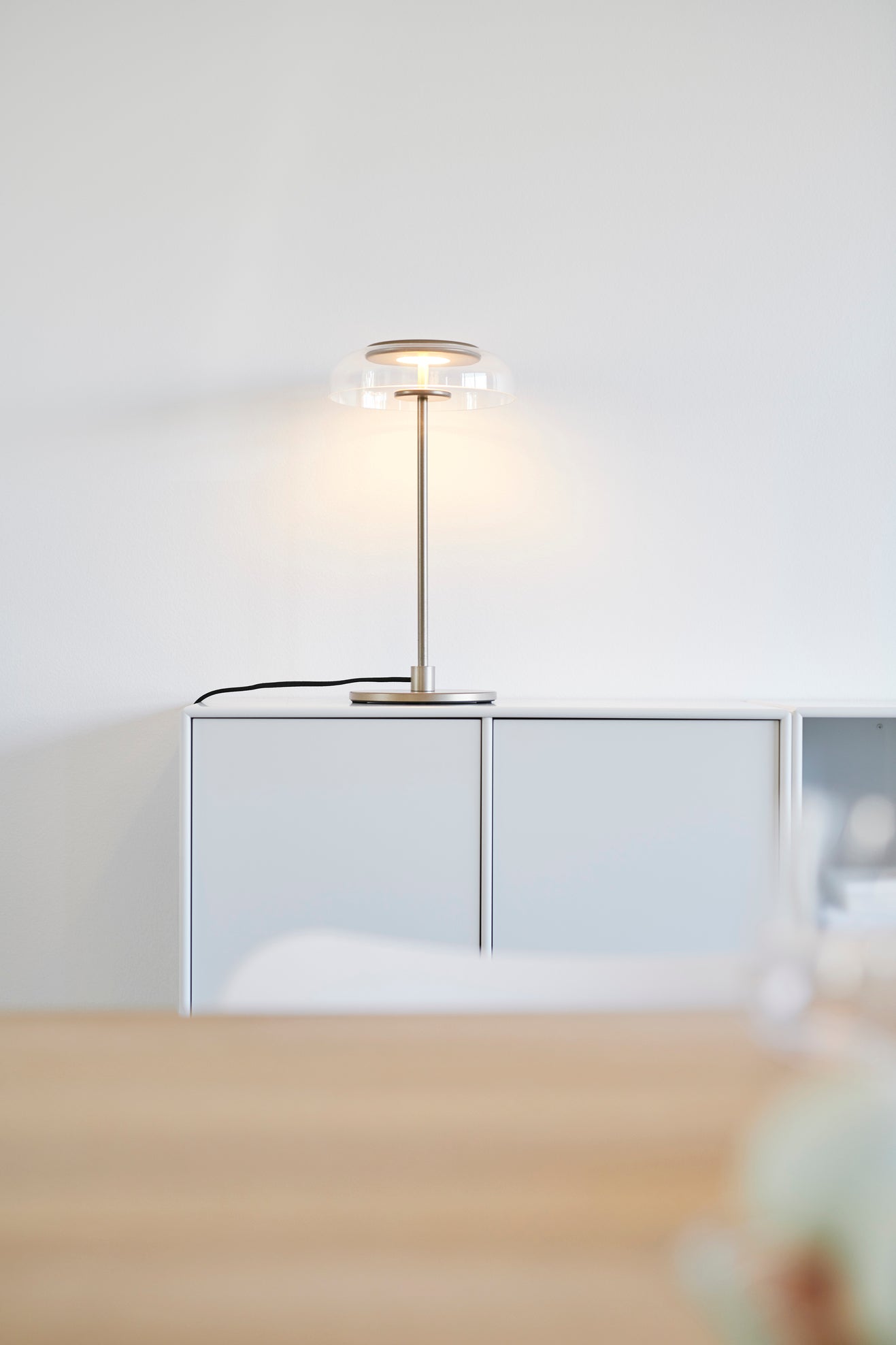 Bordlampe med gyldent stel og fatning samt glasskærm, i dagligstuemiljø