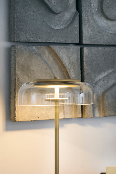 Bordlampe med gyldent stel og fatning samt glasskærm, i dagligstuemiljø
