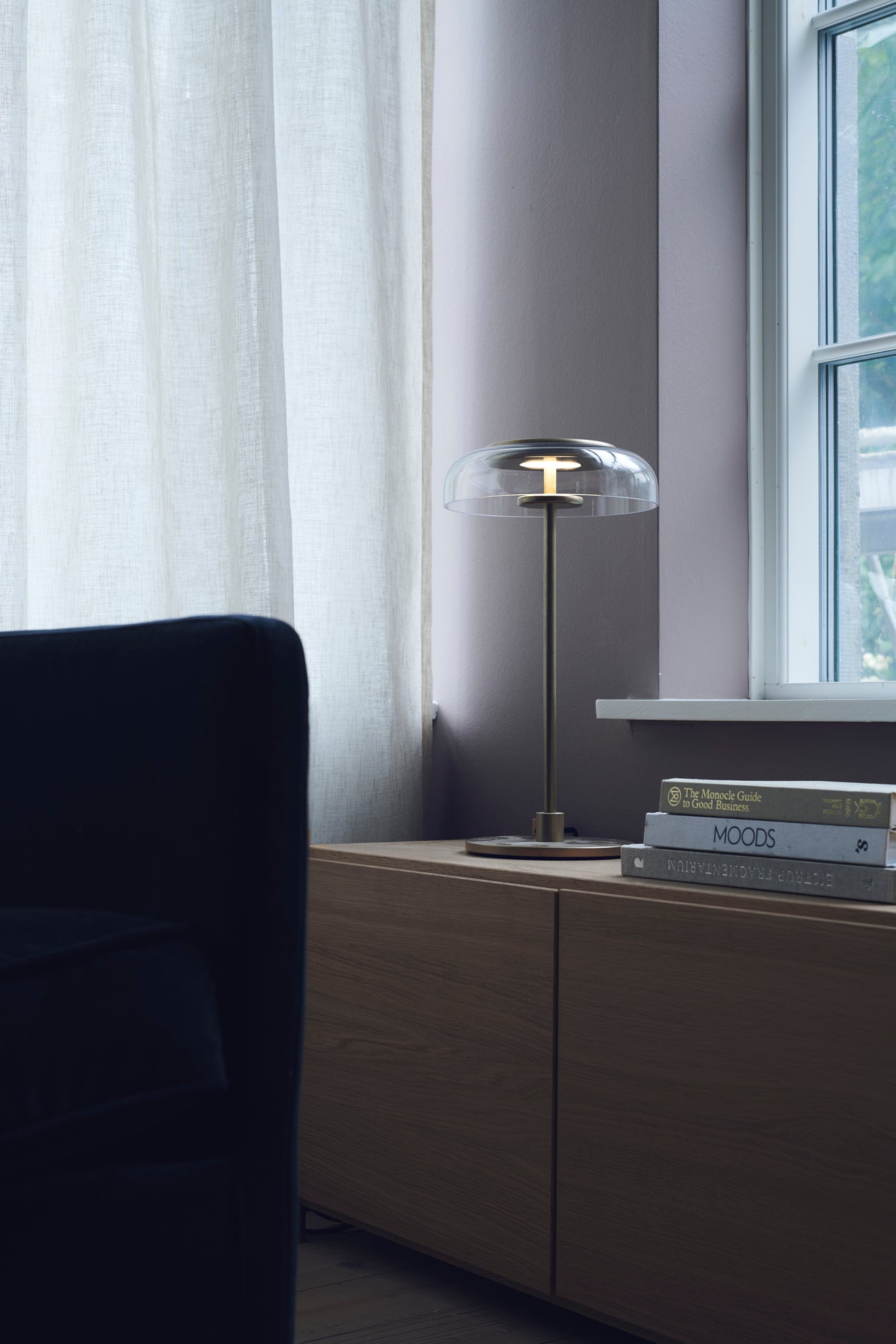 Bordlampe med gyldent stel og fatning samt glasskærm, i dagligstuemiljø