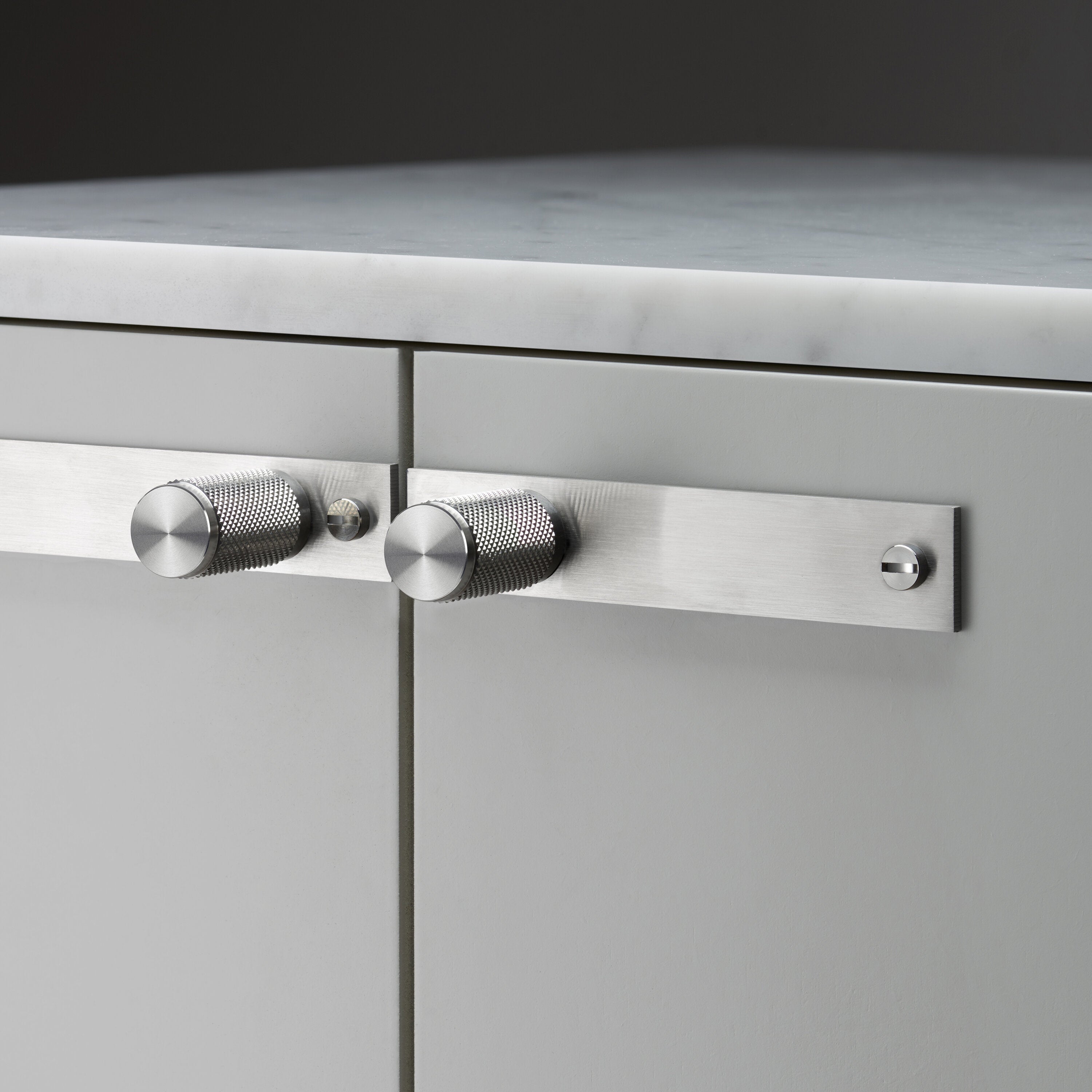 Eksklusiv møbelknop med bagplade fra Buster + Punch i rustfri stål med diamond cut (cross) mønster. Bagpladen kan bl.a. anvendes til at dække over eventuelle gamle monteringshuller.