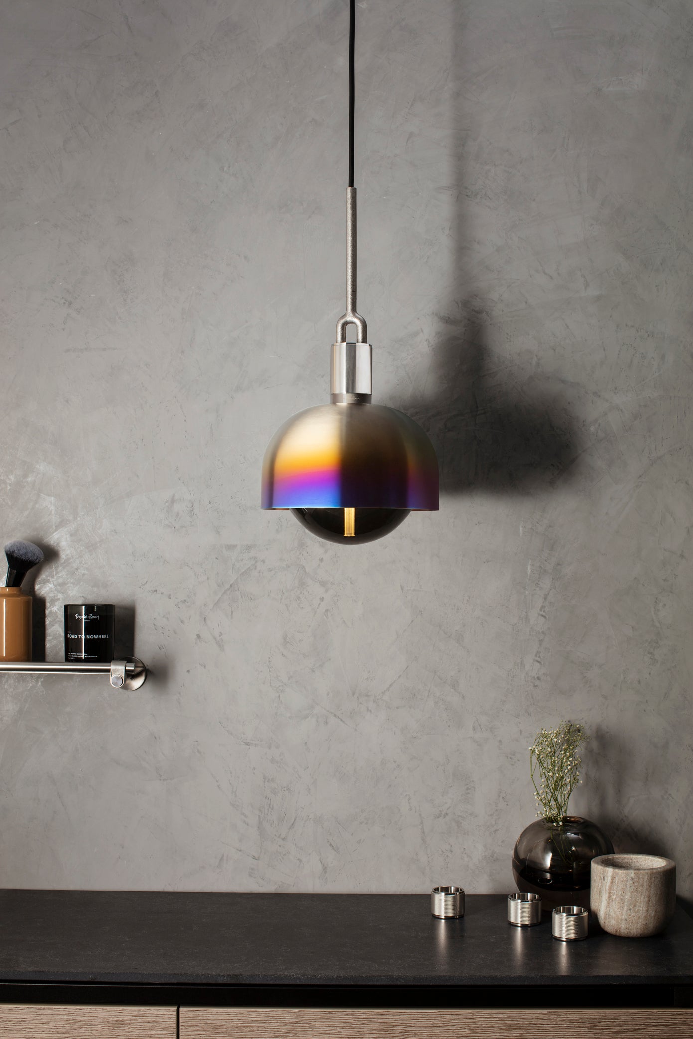 Pendel med fatning og skærm af brændt stål samt pære i røgfarvet glas, hængende over køkken