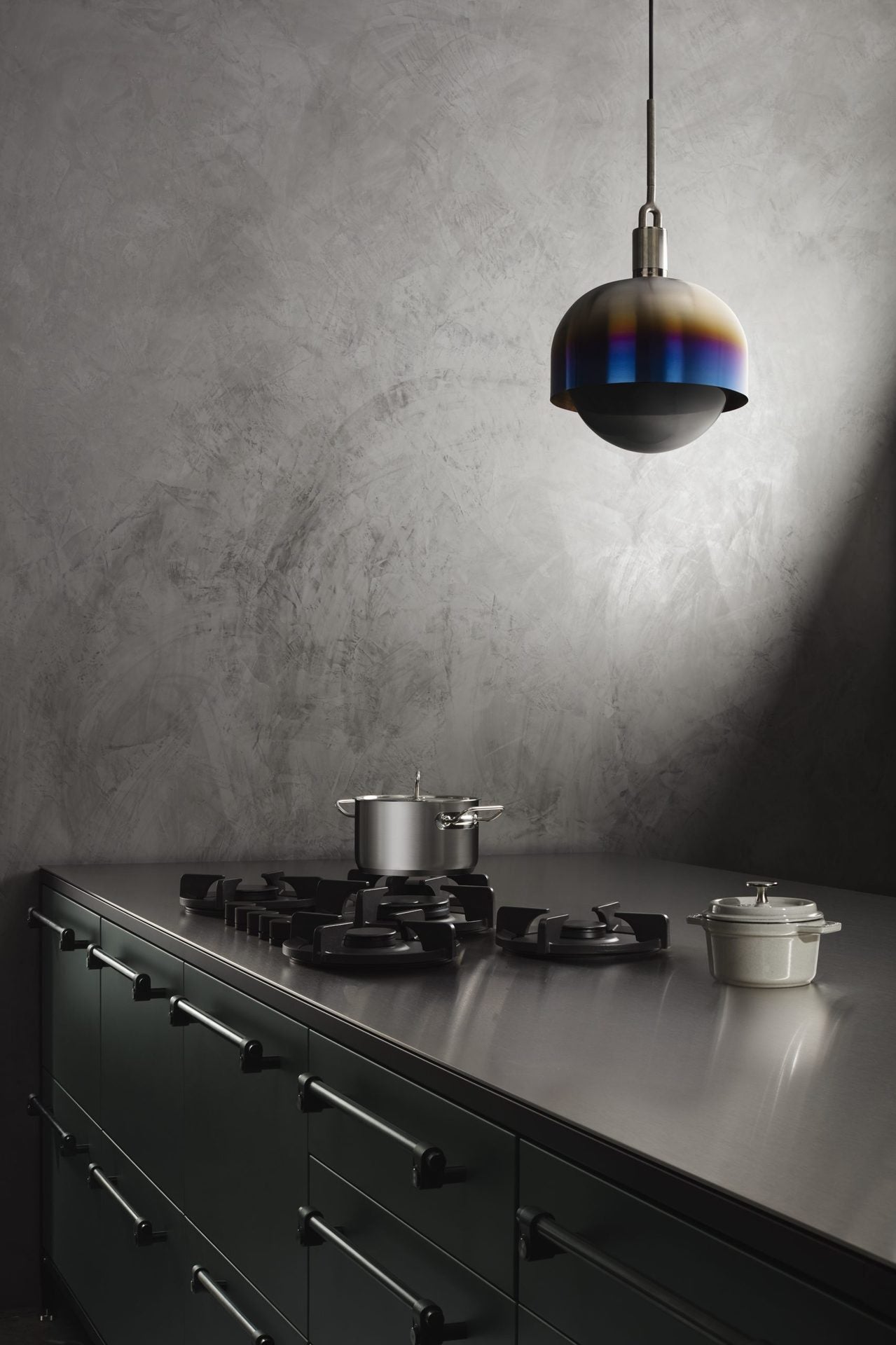 Pendel med fatning og skærm af brændt stål samt pære i røgfarvet glas, hængende over køkken