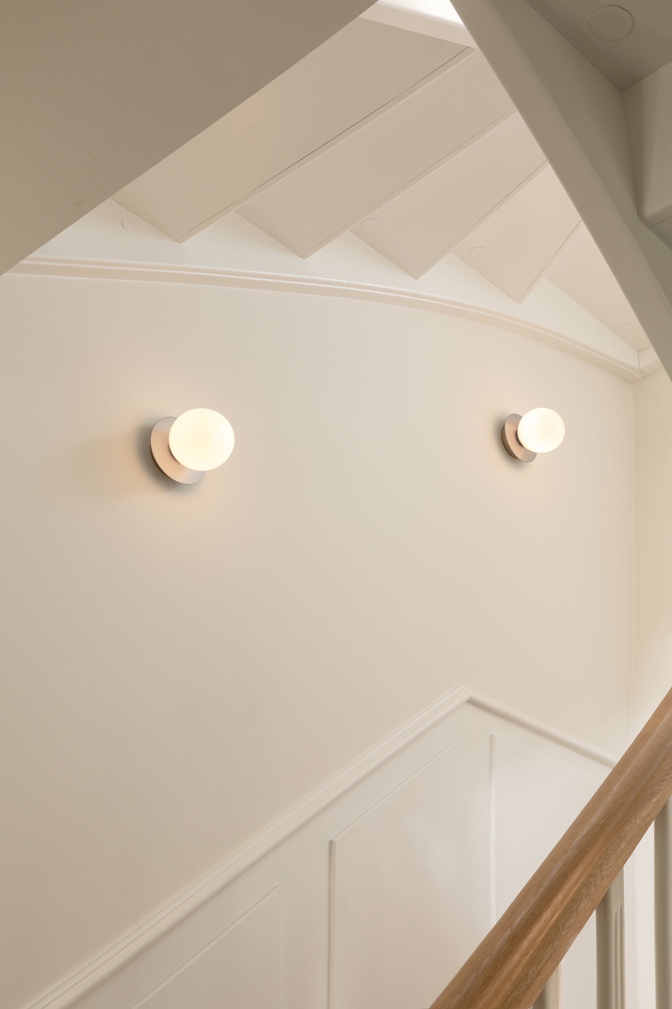 Væglamper med lampeskærme af opalglas og sølvfarvet fatning, langs trappe i hall