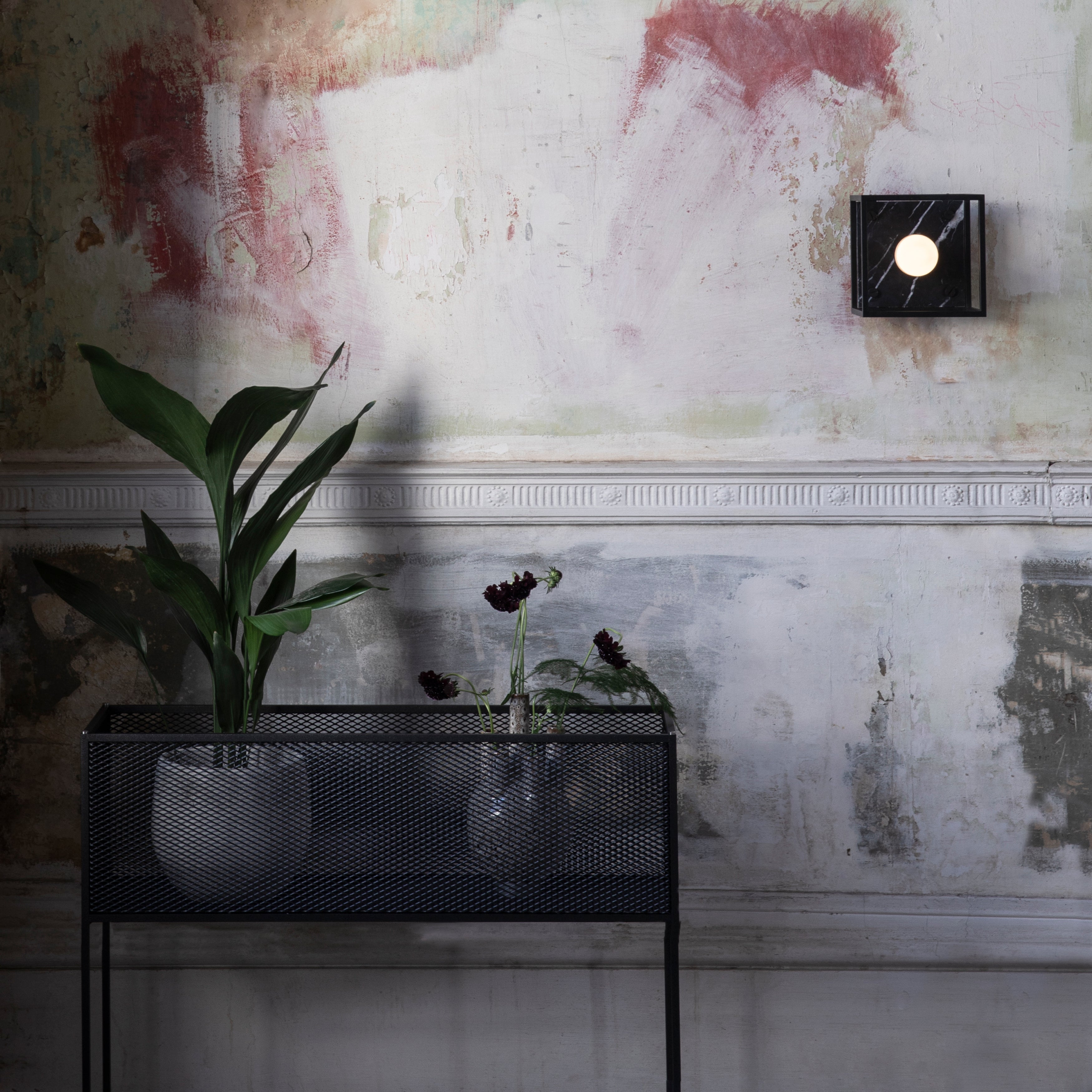 Firkantet og sort plantekasse i stålramme med meshed/hullet design på siderne. Der medfølger detaljer/skruer i både stål og messing.