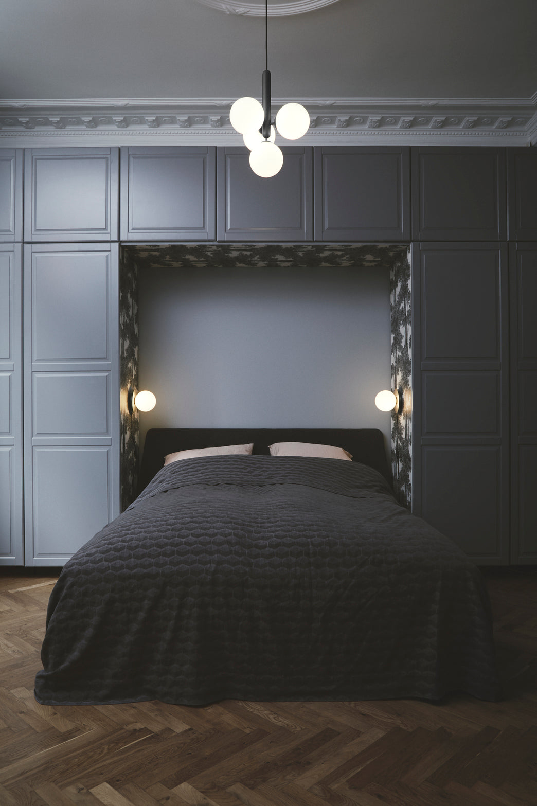 Pendel bestående af fire runde glasskærme af opalglas samt mørkegrå fatning, hængende i soveværelse