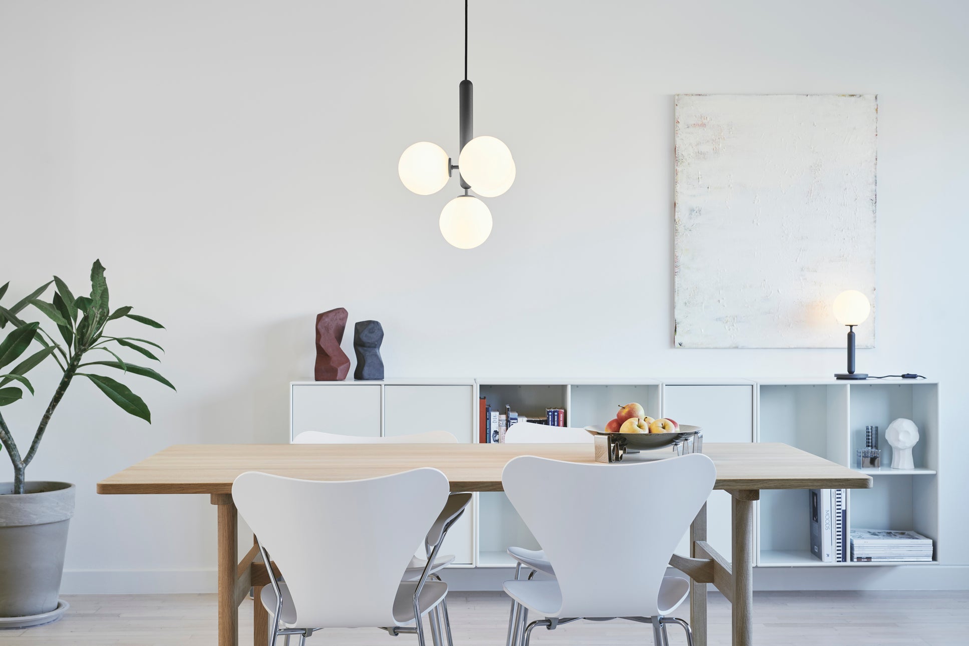 Pendel bestående af fire runde glasskærme af opalglas samt mørkegrå fatning, hængende over spisebord