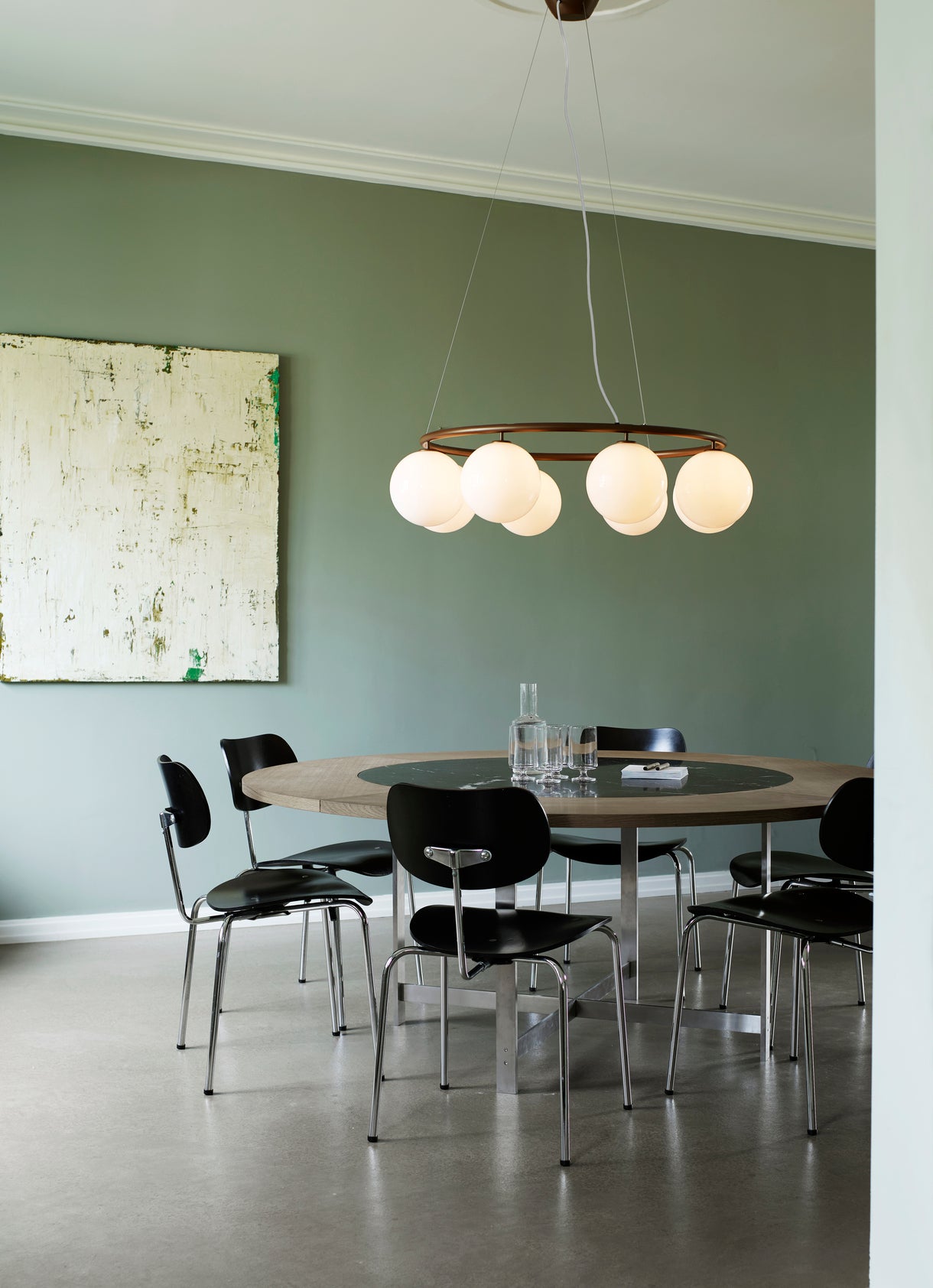 Lysekrone bestående af otte runde skærme i opalglas samt bruneret krone, hængende over spisebord