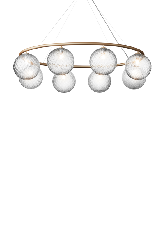 Lysekrone bestående af otte runde skærme i klart optikglas samt messingfarvet krone, på hvid baggrund