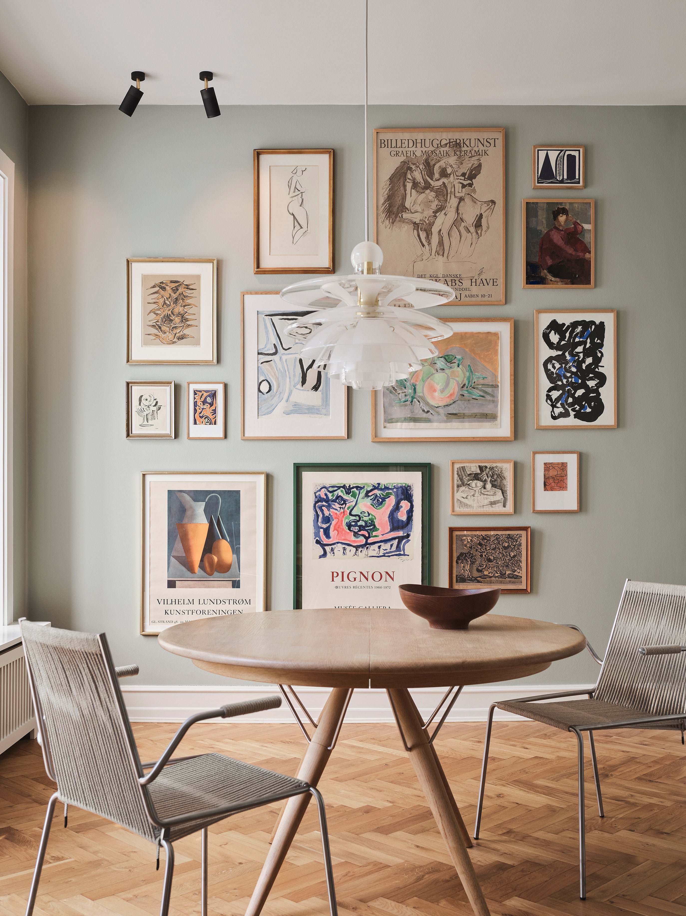 Spisestuemiljø med bord og stole. Loftspots sætter spotlys på kunst på væggen.