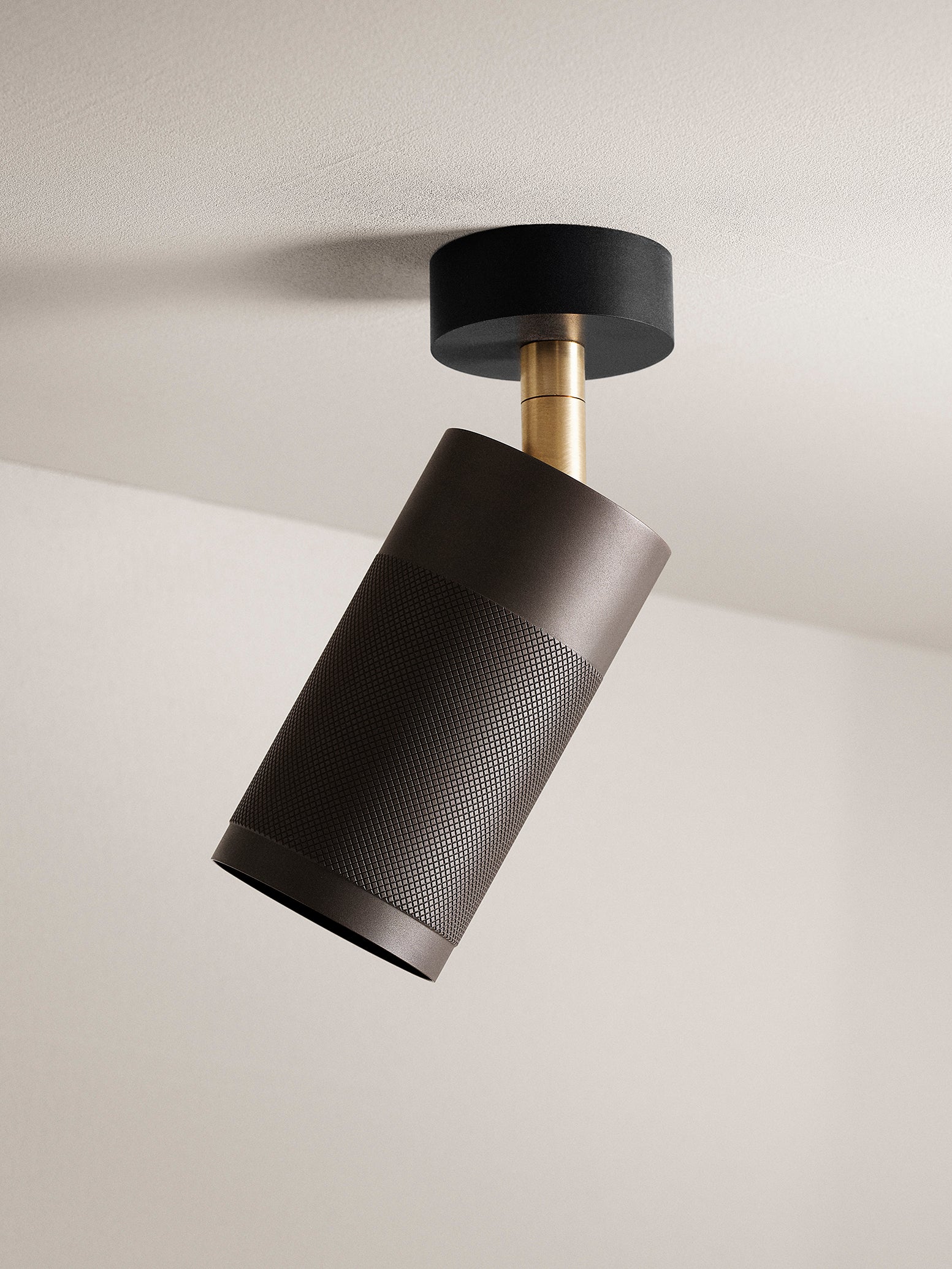 Loftspot af riflet sortbruneret messing, messing fod samt sort baldakin, monteret på lyst loft of med lys baggrund.