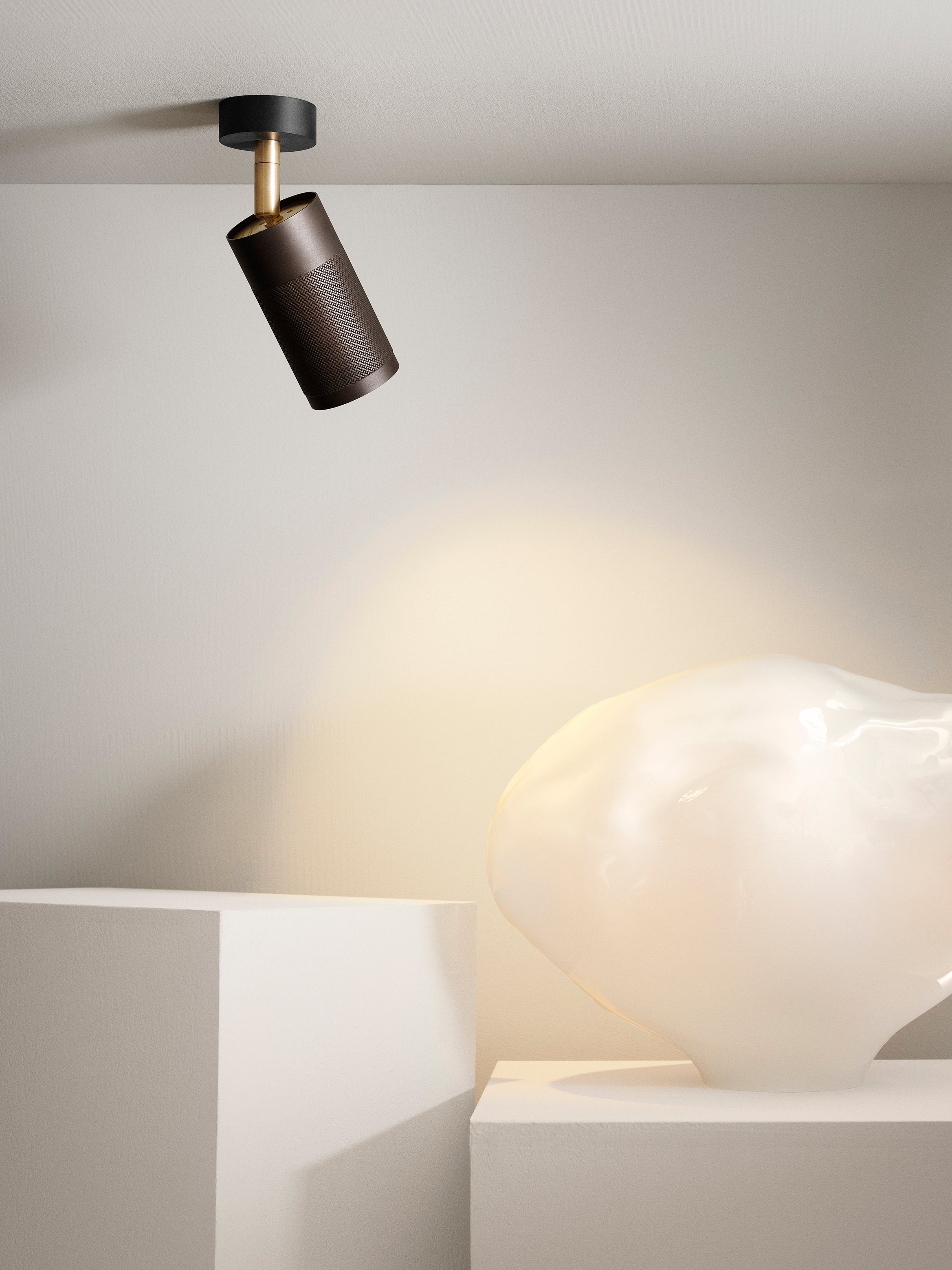 Loftspot af riflet sortbruneret messing, messing fod samt sort baldakin, med spotlys på en skulptur.