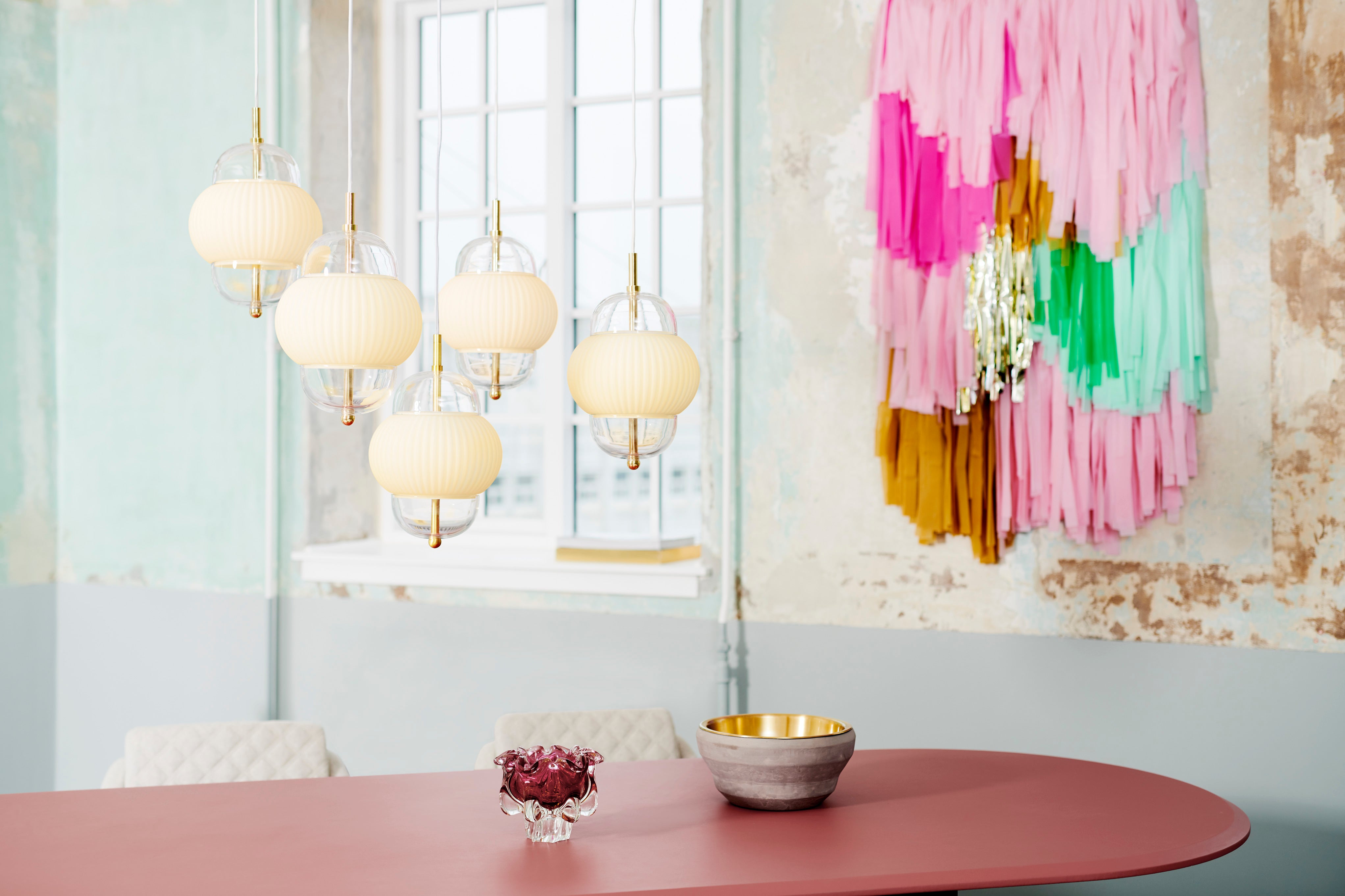 Lampe i klart glas og mat hvidt plisseret glas. Derudover har lampen detaljer i messing og en hvid stofledning.