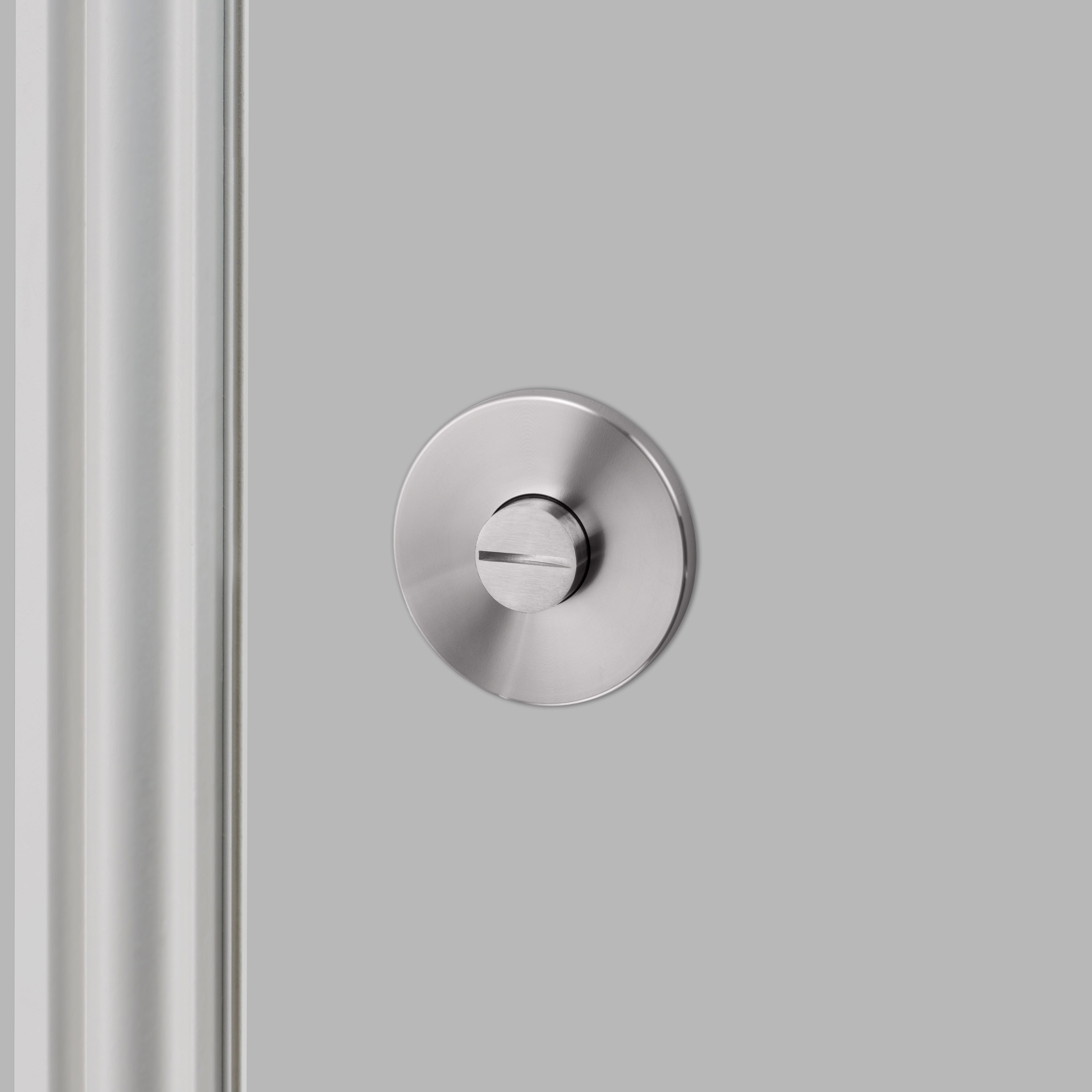 Vriderlås i rustfri stål og i eksklusivt design med linjeret mønster. Her ses bagsiden af vridelåsen.