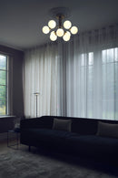 Lysekrone bestående af runde skærme i opalglas samt messingfarvet krone, i dagligstuemiljø