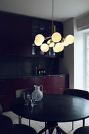 Lysekrone bestående af runde skærme i opalglas samt messingfarvet krone, i køkken