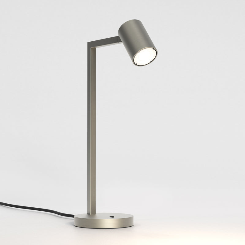 Stålfarvet bordlampe med justerbar hoved. Lampen har et enkelt design med firkantede linjer/vinkler.