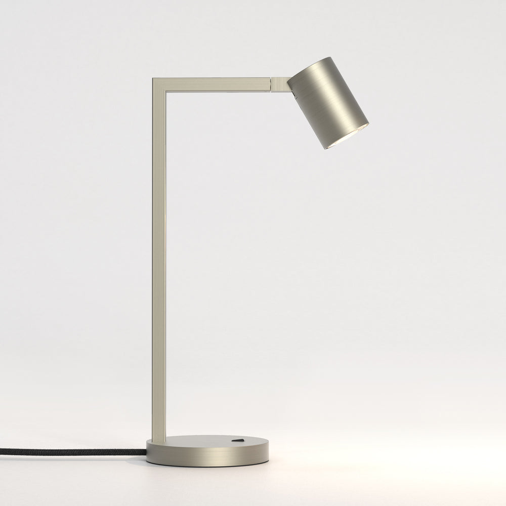 Stålfarvet bordlampe med justerbar hoved. Lampen har et enkelt design med firkantede linjer/vinkler.