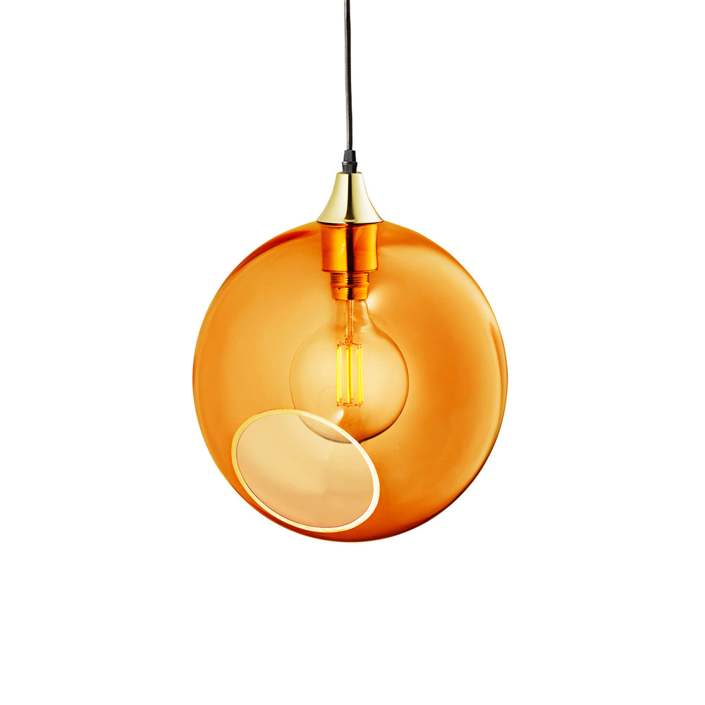 Rund lampe i orange/gult glas og med et afskåret stykke med guldkant og kig til pæren. Fatningen og rosetten er guldfarvet og ledningen er af sort stof.