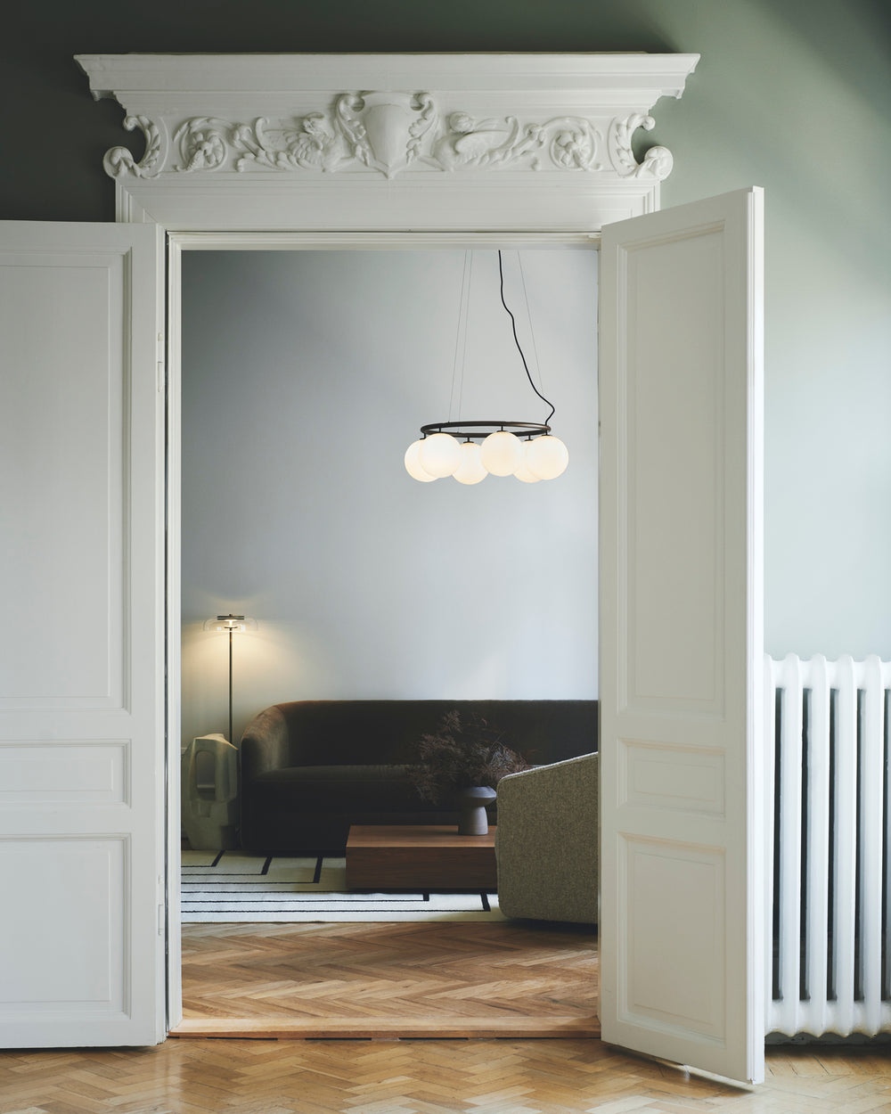 Gulvlampe med gyldent stel og fatning samt klar glasskærm, i dagligstuemiljø