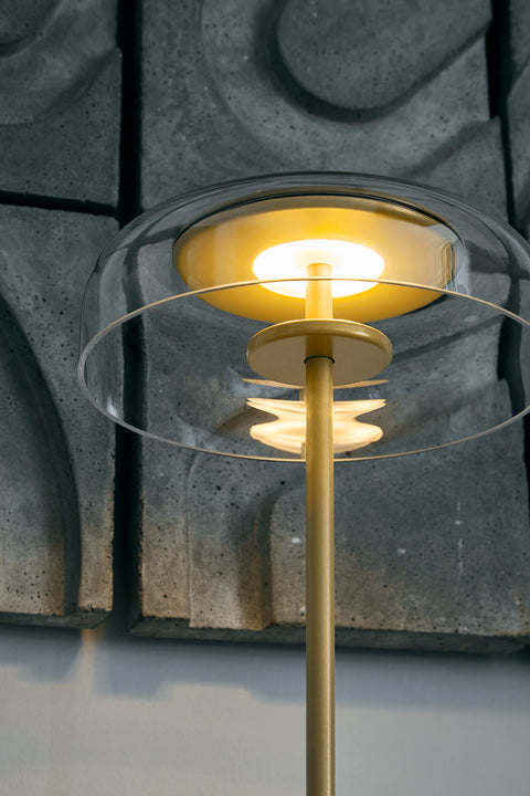 Bordlampe med gyldent stel og fatning samt glasskærm, i dagligstuemiljø