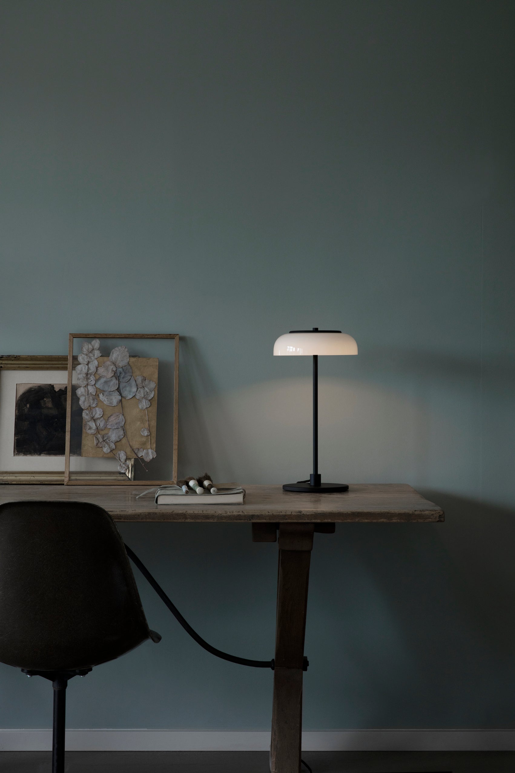 Bordlampe med sort stel og fatning og glasskærm i opalglas, på skrivebord