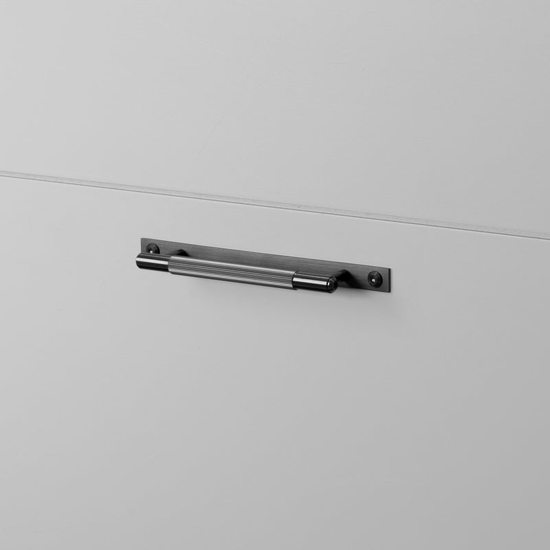 Køkkengreb til køkkenfronter fra Buster + Punch i rustfri stål med en gun metal overflade, bagplade og linjeret mønster.