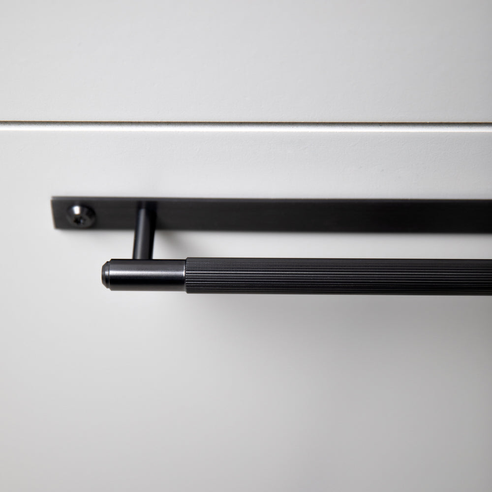 Køkkengreb til køkkenfronter fra Buster + Punch i rustfri stål med en gun metal overflade, bagplade og linjeret mønster.
