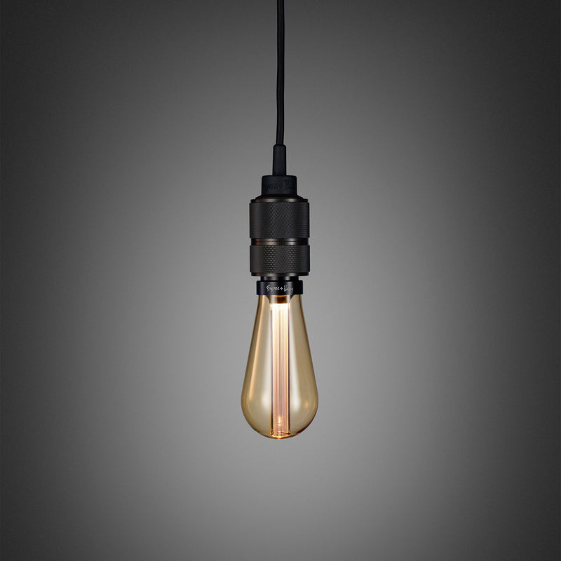 Enkel pendel lampe med fatning i bruneret massiv messing med diamond cut (cross) mønster fra Buster + Punch. Lampen har en krog i bruneret massiv messing, som gør det muligt at justere højden på lampen.