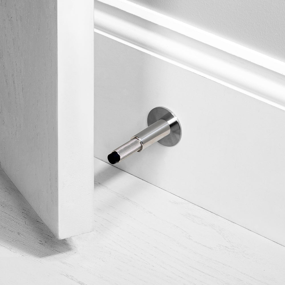 Eksklusiv dørstopper til vægmontering i massiv rustfri stål fra Buster + Punch med diamond cut (cross) mønster.