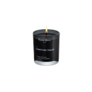 Duftlys af sort voks i røgfarvet glas med tændt flamme, på hvid baggrund.