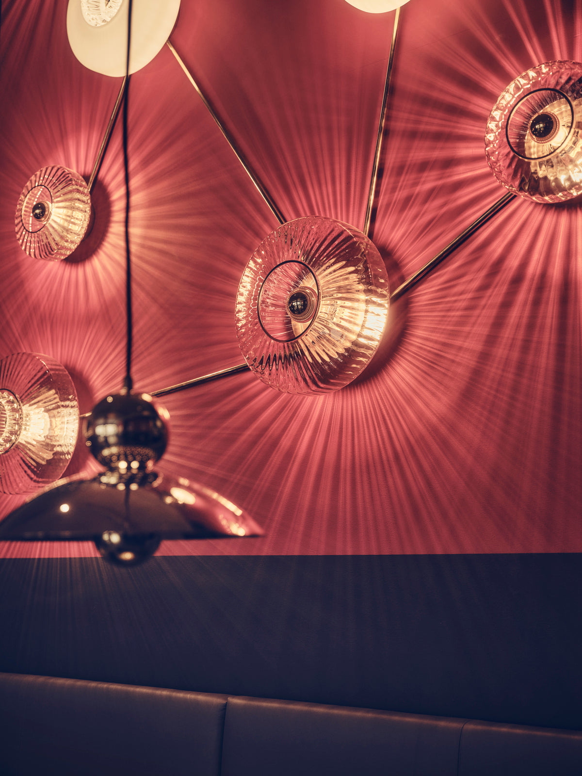 Rund væglampe i klart plisseret glas, som skaber et lysspil på væggen