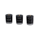3 duftlys af sort voks i røgfarvede glas, på hvid baggrund.