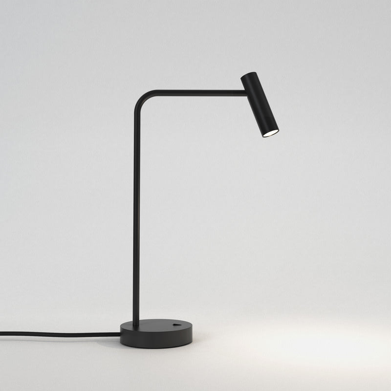 Bordlampe i sort aluminium med bøjet hals, rund fod og et aflangt, rundt, justerbart hoved.