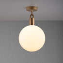 Loftlampe med rund skærm i opalglas og fatning i messing, på grå baggrund