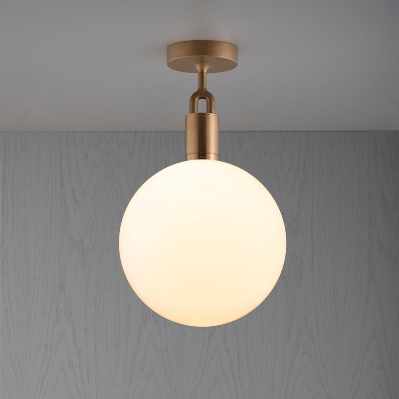 Loftlampe med rund skærm i opalglas og fatning i messing, på grå baggrund