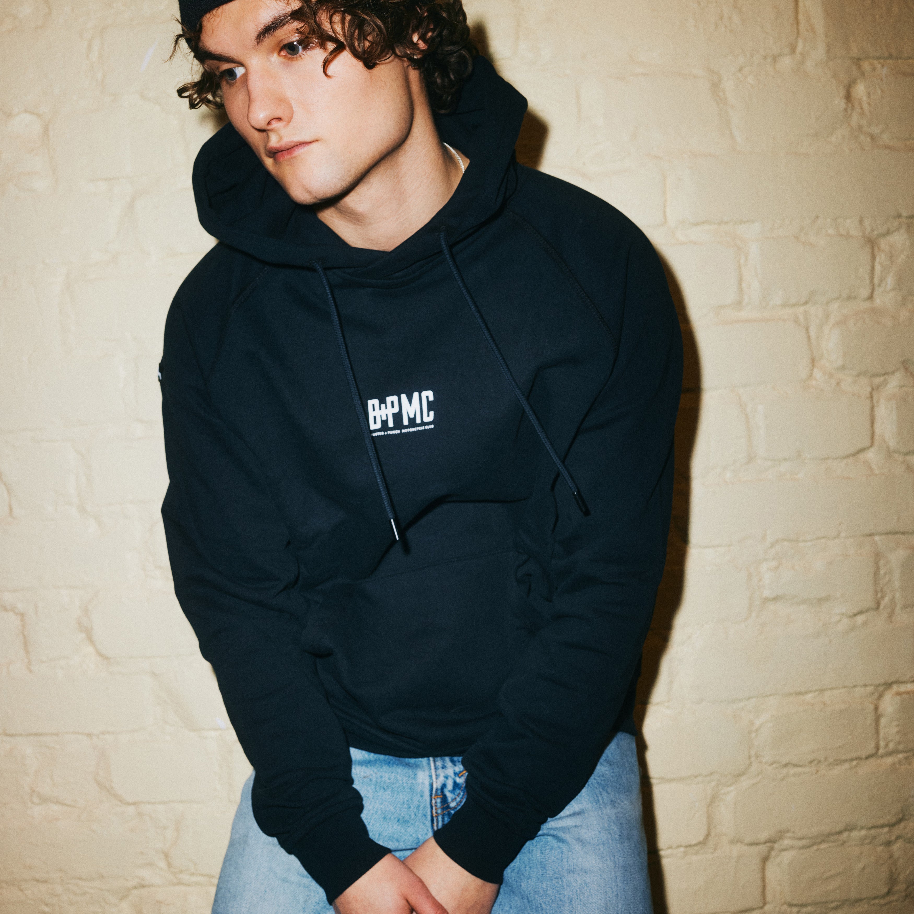 Kraftig sort hættetrøje med Buster + Punch logo på brystkasse og skulder.