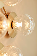 Close-up af væglampe med lampeskærme af klart optikglas og gylden fatning og stel
