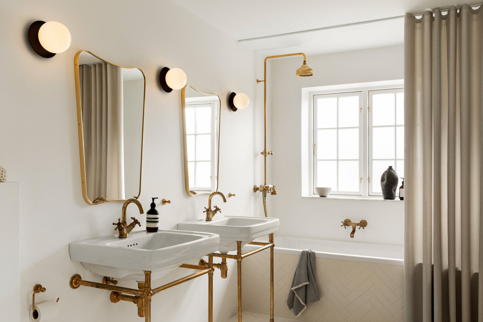 Tre væglamper med lampeskærme af opalglas og gylden fatning, ved spejle på badeværelse