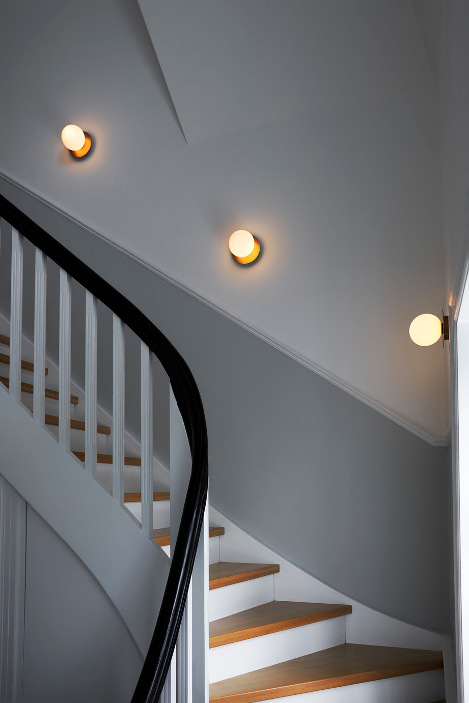 Tre væglamper med lampeskærme af opalglas og gylden fatning, langs trappe i hall