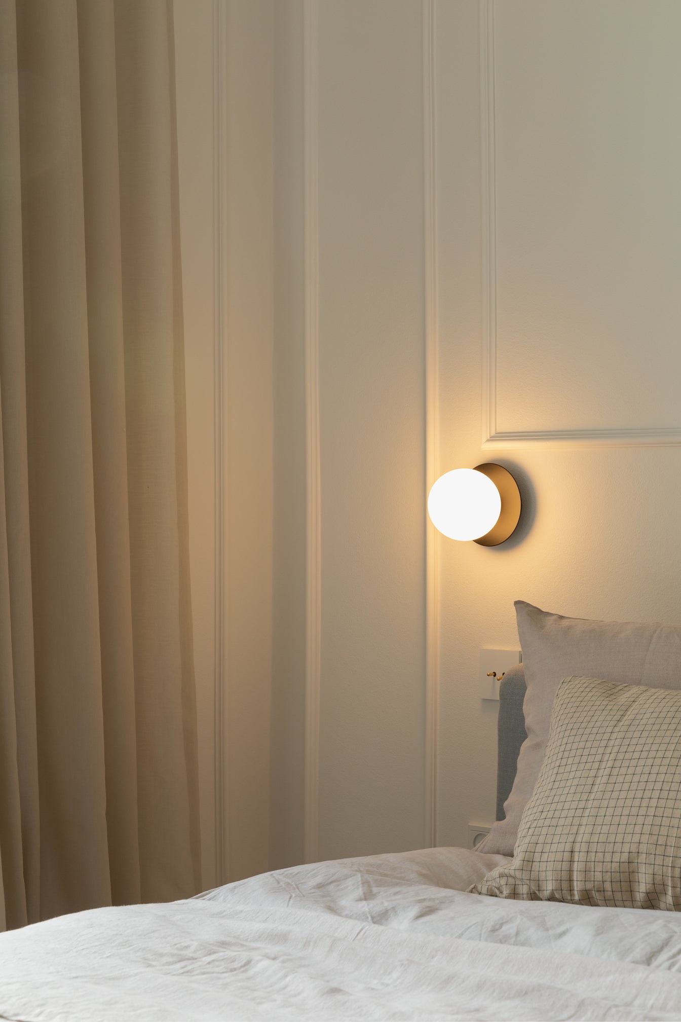 Væglampe med lampeskærm af opalglas og gylden fatning, i soveværelse