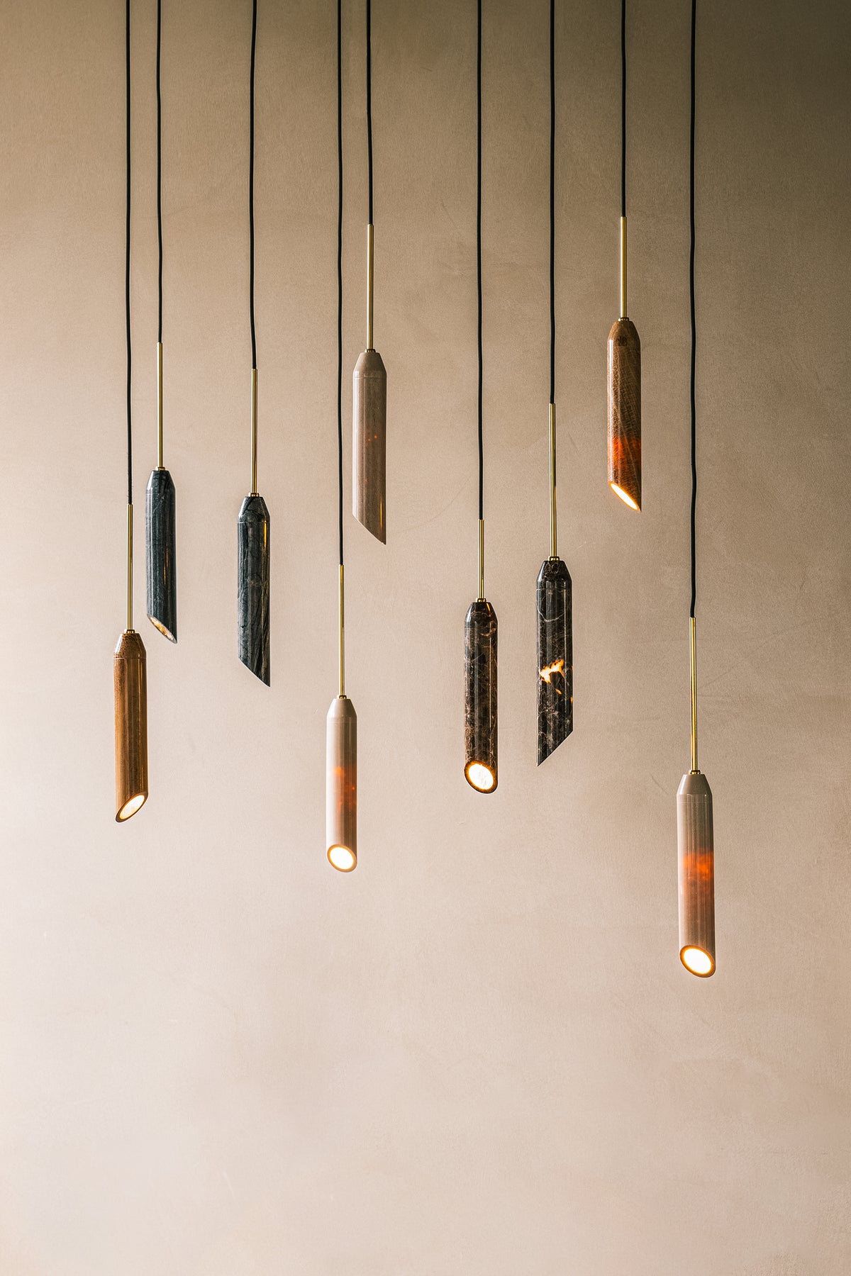 Pendel lampe i gyldent marmor med diagonalt snit og med guldfarvet detaljer. Lampen har en sort stofledning.