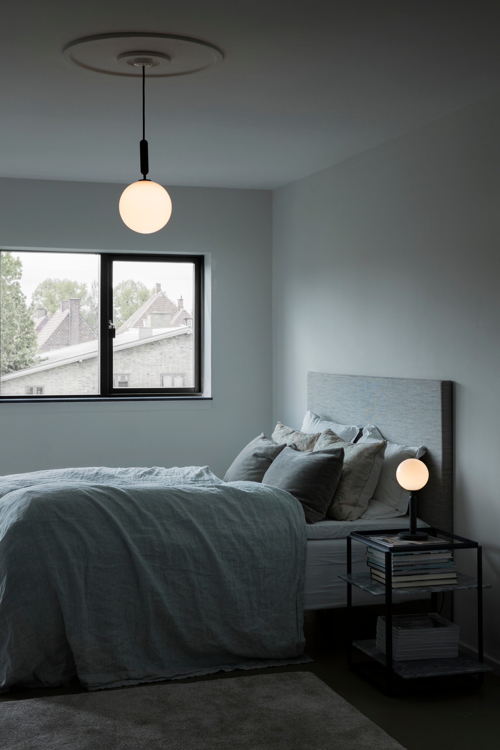 Pendel med rund skærm af opalglas og aflang grå fatning, i soveværelse