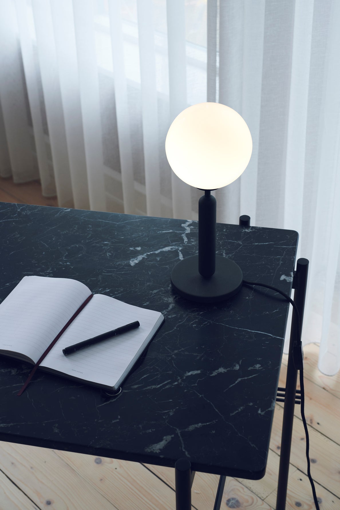 Bordlampe med rund skærm af opalglas og mørkegråt stel, på skrivebord