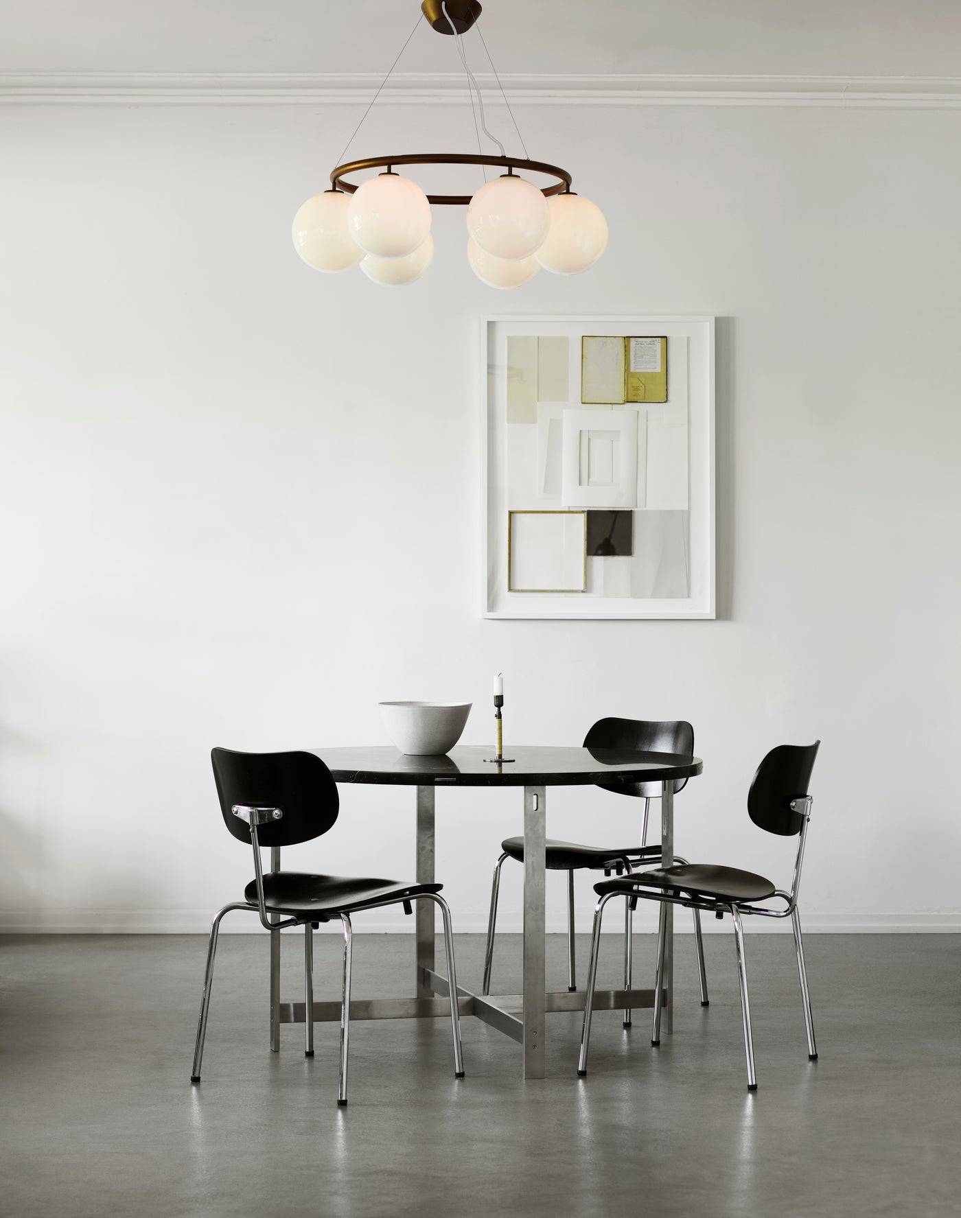 Lysekrone bestående af seks runde skærme i opalglas samt bruneret krone, i spisestuemiljø over spisebord