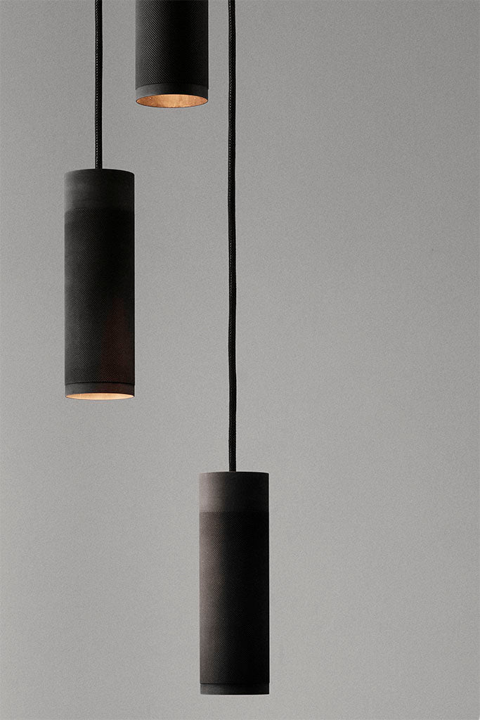 Nærbillede af loftlampe med tre pendler i massiv sort bruneret messing med sort stofledning 